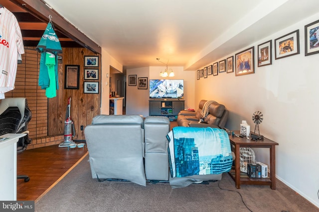 carpeted living area with an inviting chandelier and wooden walls