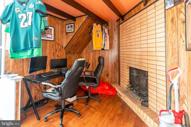 office featuring a brick fireplace, beam ceiling, wood walls, and wood finished floors