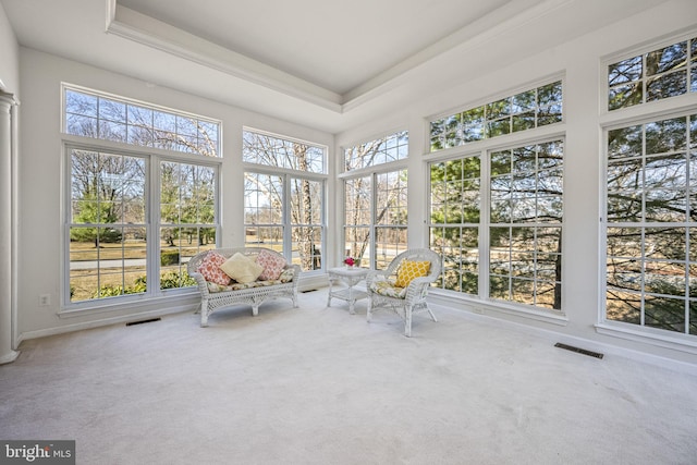 unfurnished sunroom featuring visible vents, a raised ceiling, and a healthy amount of sunlight