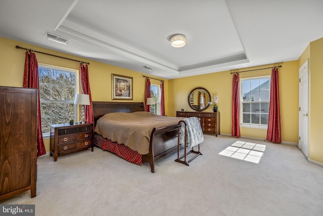 carpeted bedroom with a tray ceiling and visible vents