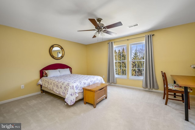 bedroom with visible vents, light colored carpet, baseboards, and ceiling fan