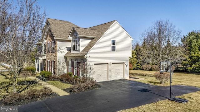 view of front facade featuring a front yard, an attached garage, driveway, and a shingled roof