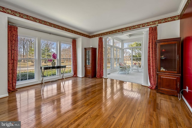 interior space with baseboards, ornate columns, and hardwood / wood-style floors