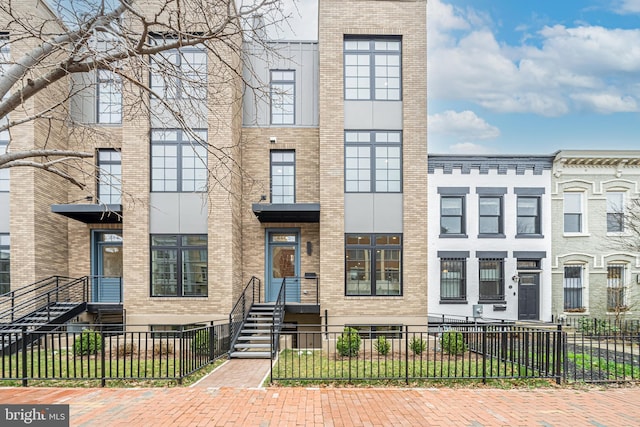 townhome / multi-family property featuring brick siding and a fenced front yard