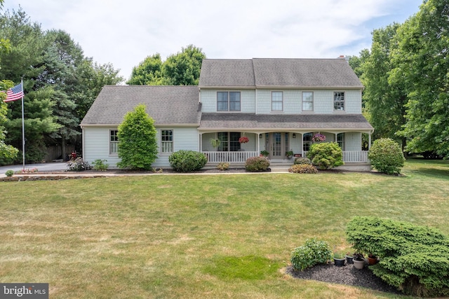 view of front of house with covered porch, a front lawn, and a shingled roof