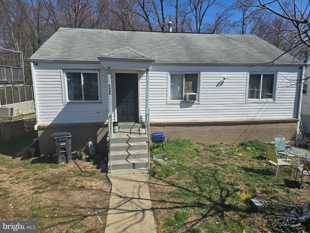 view of front facade with cooling unit, brick siding, and fence