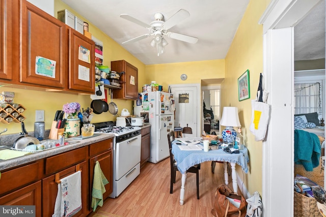 kitchen featuring white appliances, brown cabinetry, ceiling fan, light countertops, and light wood-type flooring