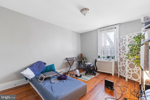 sitting room featuring baseboards, wood-type flooring, and radiator heating unit