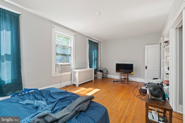 living room featuring cooling unit, light wood-style flooring, radiator, and baseboards
