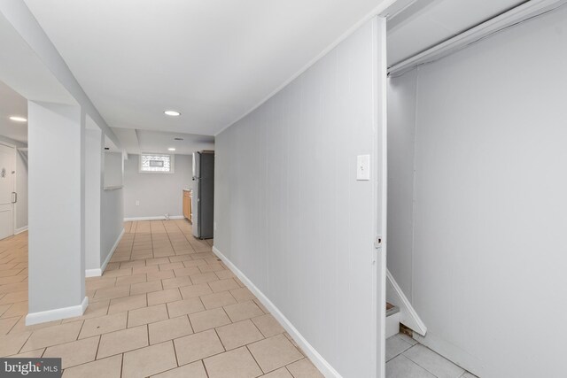 hallway featuring light tile patterned floors and baseboards