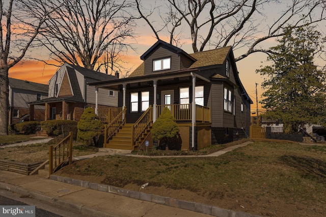 bungalow-style house featuring stairway, a yard, and covered porch