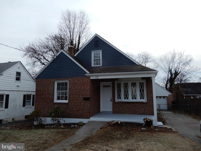 view of front of property featuring brick siding, fence, and a chimney