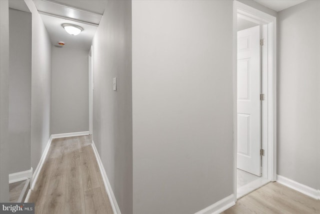 hall with baseboards and light wood-style floors