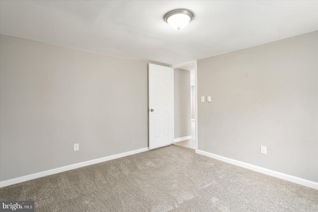 carpeted empty room featuring baseboards