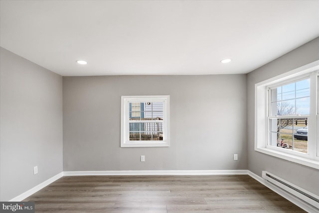 unfurnished room featuring a baseboard radiator, baseboards, wood finished floors, and recessed lighting