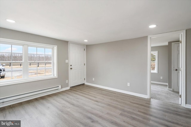 spare room featuring baseboards, a baseboard heating unit, wood finished floors, and recessed lighting