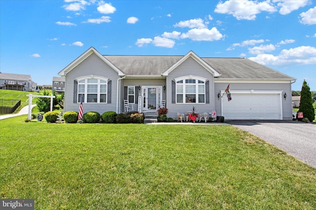 ranch-style home featuring an attached garage, driveway, a front yard, and roof with shingles