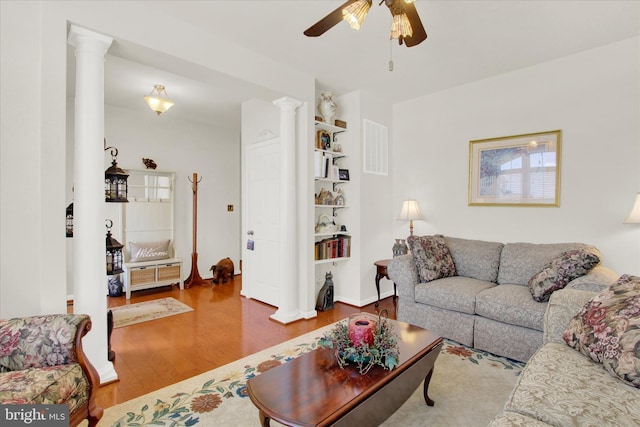 living area featuring wood finished floors, visible vents, ornate columns, and ceiling fan