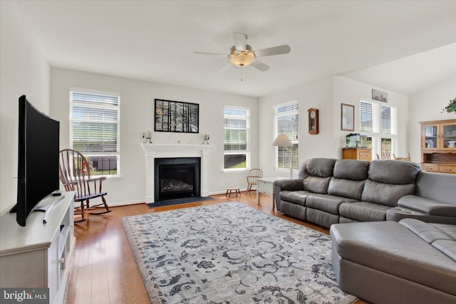 living room with wood finished floors, a fireplace with flush hearth, a ceiling fan, and baseboards