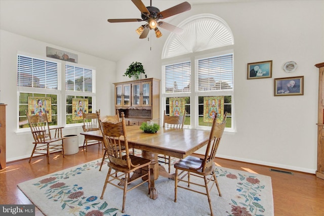 dining space with a wealth of natural light, high vaulted ceiling, wood finished floors, and a ceiling fan