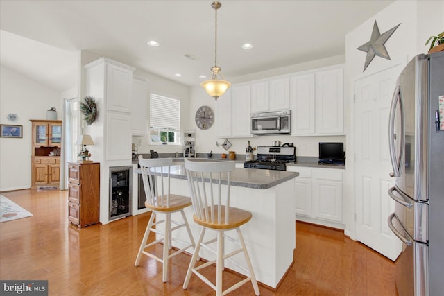 kitchen with appliances with stainless steel finishes, beverage cooler, white cabinets, and light wood finished floors