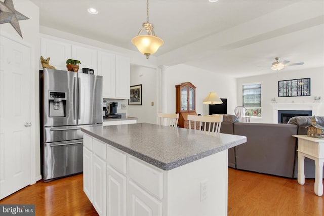 kitchen with stainless steel fridge, ceiling fan, a center island, and light wood finished floors