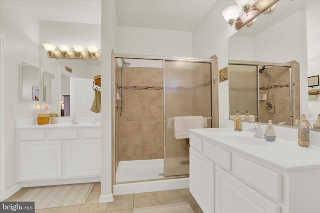 bathroom with tile patterned floors, a stall shower, two vanities, and a sink