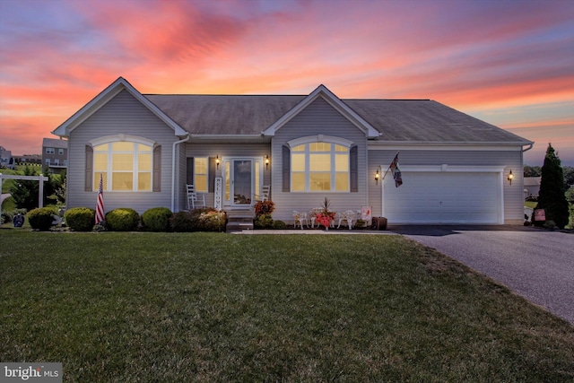 ranch-style home with aphalt driveway, a lawn, an attached garage, and a shingled roof