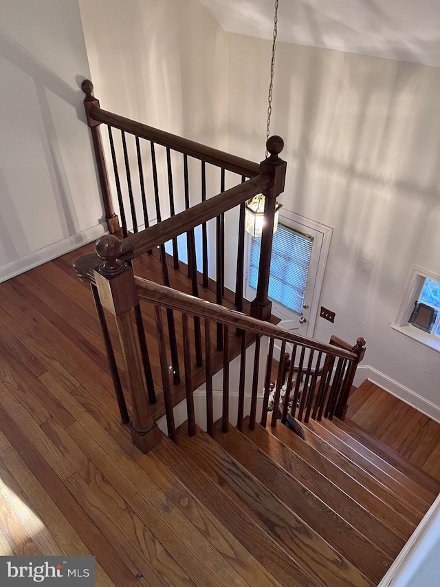 staircase with hardwood / wood-style floors, a high ceiling, and baseboards