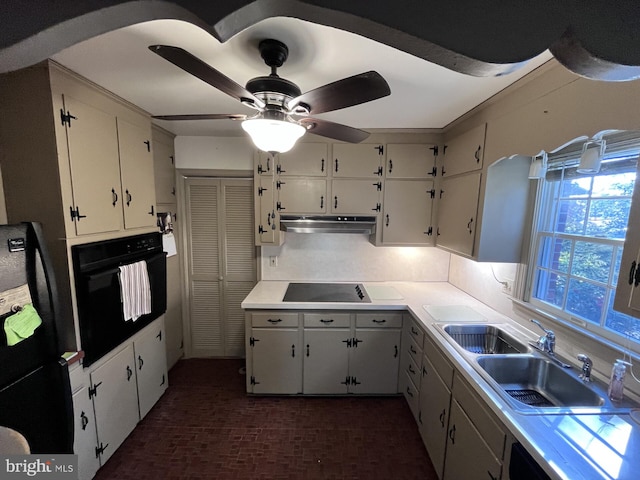 kitchen with brick floor, a sink, black appliances, under cabinet range hood, and tasteful backsplash