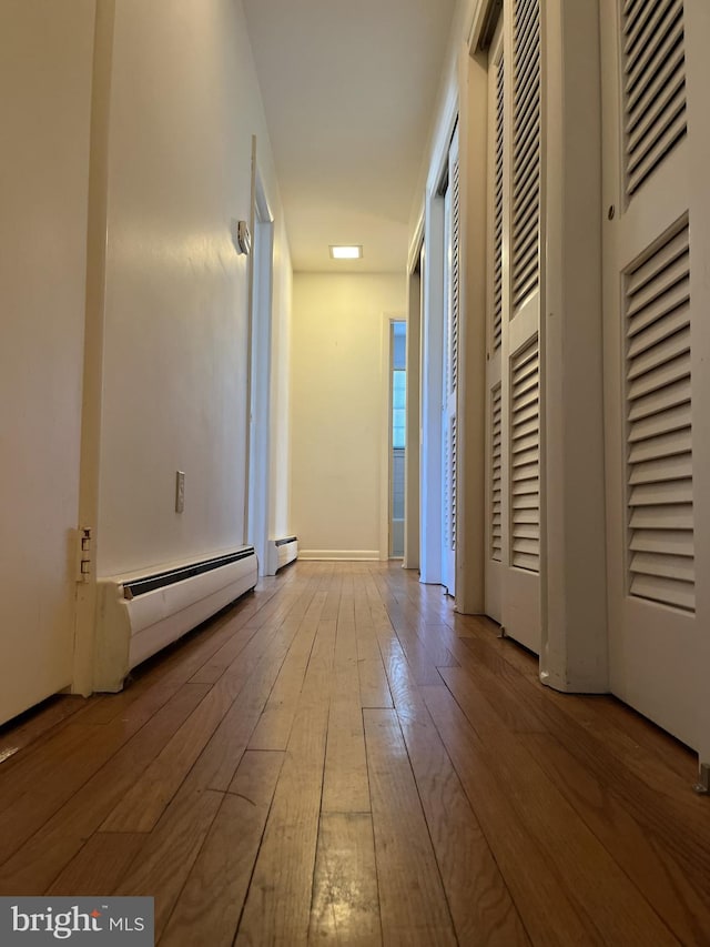 corridor with hardwood / wood-style flooring and a baseboard radiator