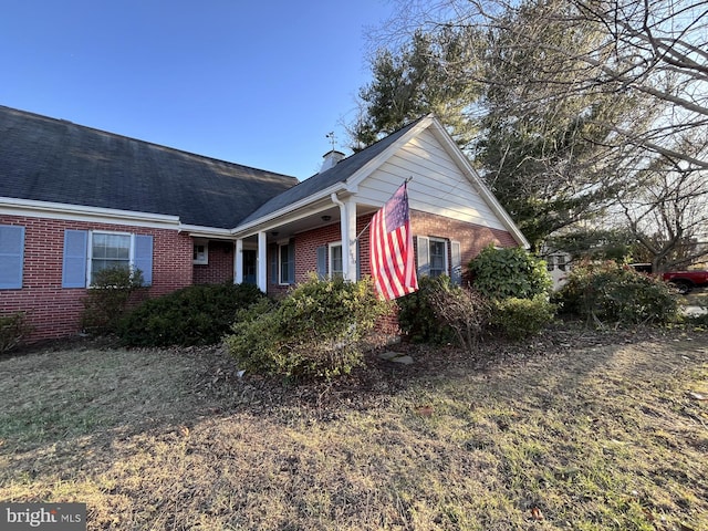 view of home's exterior with brick siding and a shingled roof