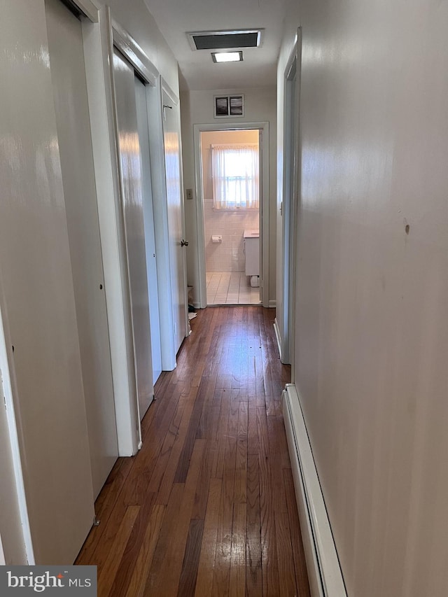 hall featuring dark wood finished floors, visible vents, and baseboard heating