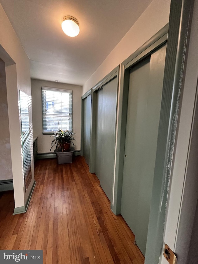 hallway featuring hardwood / wood-style floors, baseboards, and baseboard heating