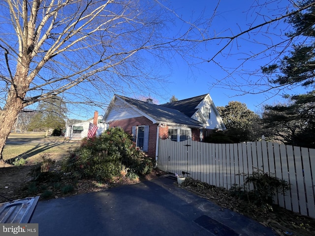 view of home's exterior featuring a fenced front yard, brick siding, and a chimney