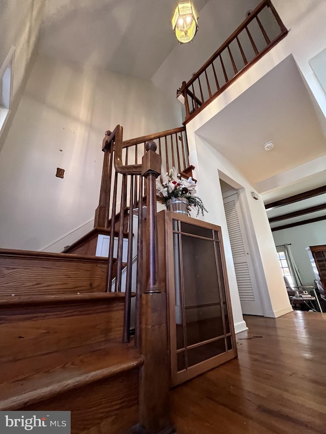 staircase featuring beamed ceiling and wood finished floors