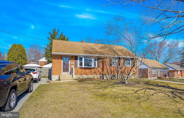 view of front of house with brick siding, a front lawn, and a shingled roof