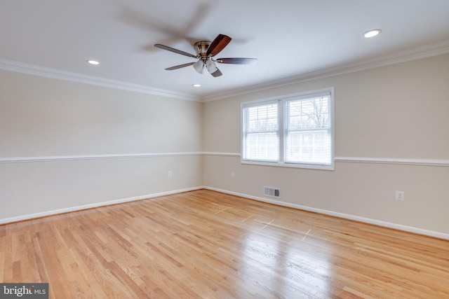 spare room with visible vents, baseboards, wood finished floors, and crown molding