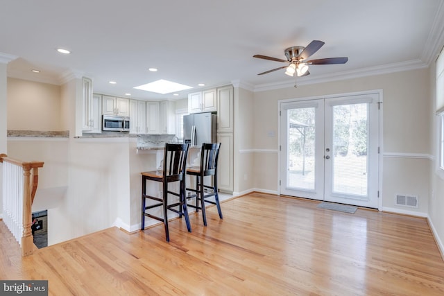 kitchen with visible vents, a breakfast bar area, light wood-style flooring, appliances with stainless steel finishes, and french doors