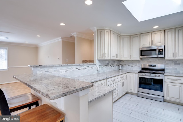 kitchen featuring tasteful backsplash, a peninsula, stainless steel appliances, and a kitchen breakfast bar