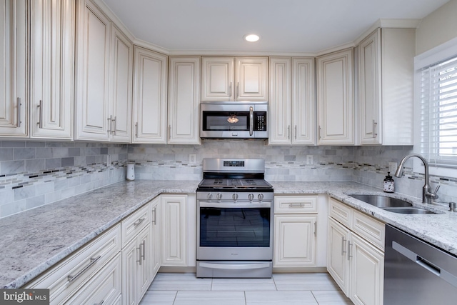 kitchen with a sink, light stone counters, backsplash, recessed lighting, and stainless steel appliances