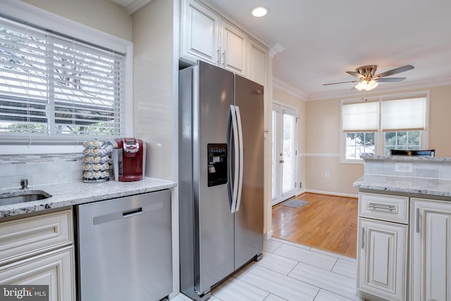 kitchen with decorative backsplash, plenty of natural light, appliances with stainless steel finishes, and crown molding