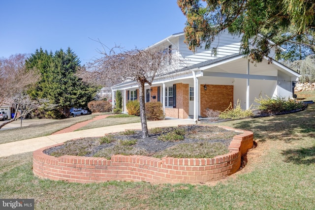 view of front of home with brick siding, a porch, and a front yard