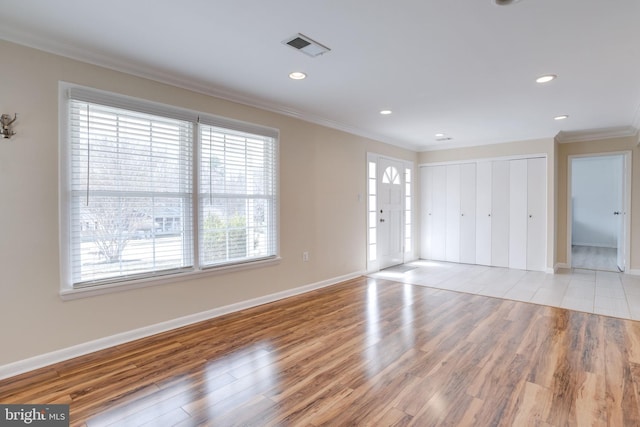 interior space featuring visible vents, crown molding, baseboards, and wood finished floors