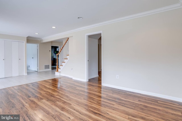 unfurnished room with stairway, crown molding, baseboards, and wood finished floors