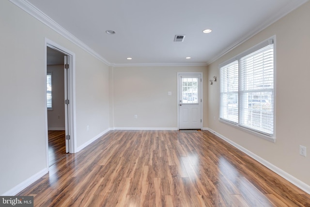 empty room with recessed lighting, baseboards, wood finished floors, and crown molding