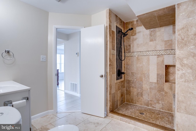 bathroom featuring vanity, visible vents, baseboards, a tile shower, and tile patterned flooring