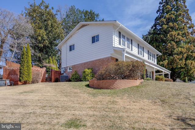 view of home's exterior featuring cooling unit, a lawn, and brick siding