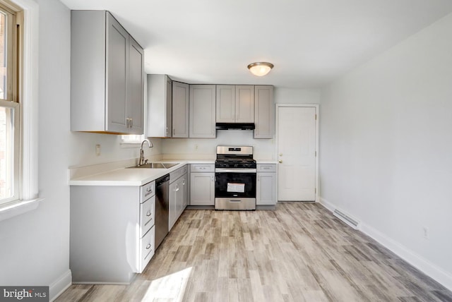 kitchen with a sink, stainless steel appliances, under cabinet range hood, and gray cabinets