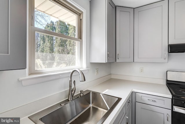 kitchen with a sink, range with gas cooktop, plenty of natural light, and gray cabinets